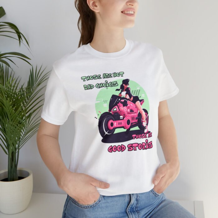 A young woman wearing a white Funny T-Shirt featuring a pink and green picture of a girl on a motorcycle saying "Those are not bad choices, those are good stories".