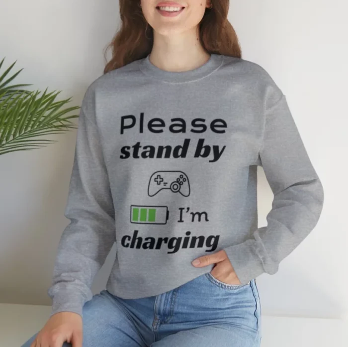 Funny Sweatshirt for Gamers featuring a picture of a gamepad and saying "Please stand by, I'm charging". Gray color