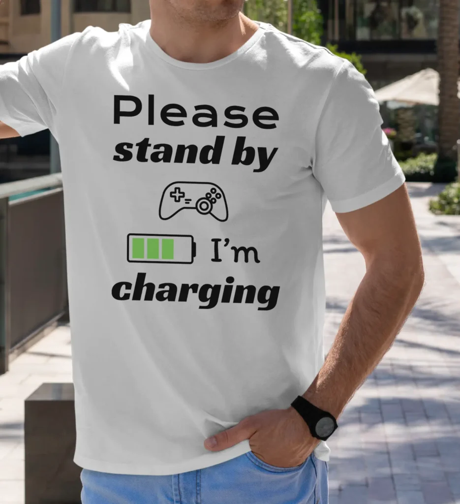 Funny T-Shirt for Gamers featuring a picture of a gamepad and saying "Please stand by, I'm charging". White color