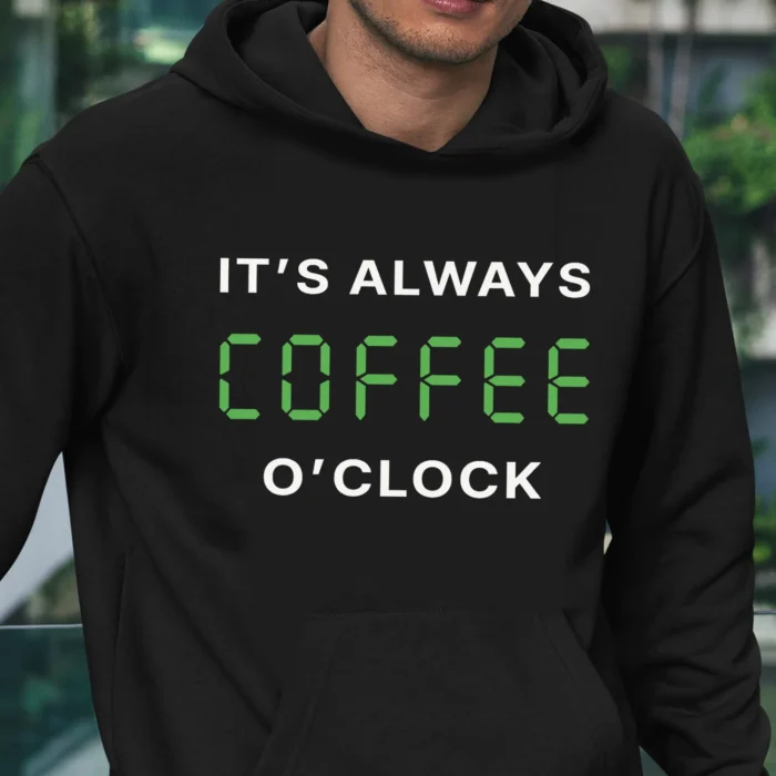 A man outside wearing a black hoodie saying "It's always coffee o'clock" in letters looking like digits on a digital clock.