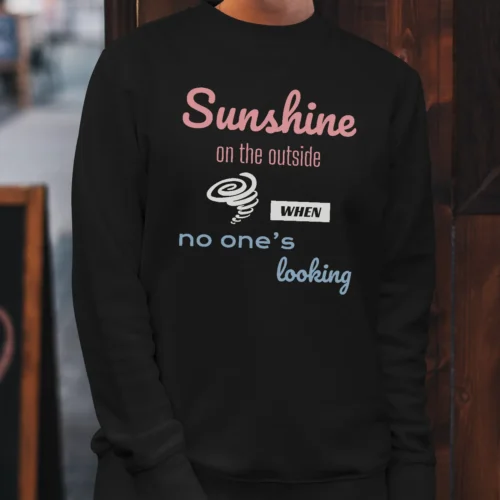 A black Funny sweatshirt featuring a picture of a little hurricane and saying "Sunshine on the outside, hurricane when no one's looking".