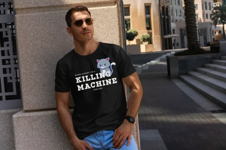 A handsome man outside wearing a black Funny T-Shirt for Cat Lovers featuring a picture of a funny angry cat and saying "When hungry, I'm a killing machine. Feed me!"