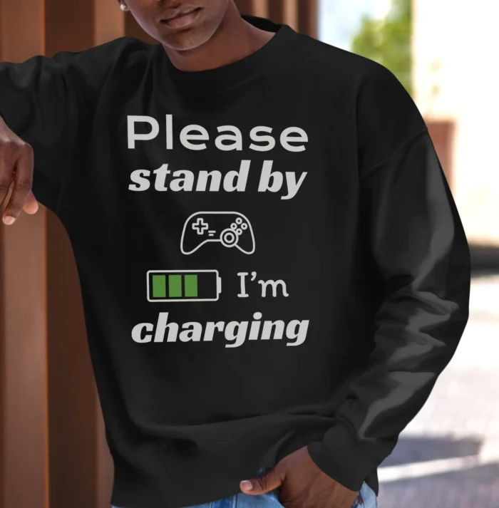 Funny Sweatshirt for Gamers featuring a picture of a gamepad and saying "Please stand by, I'm charging". Black color