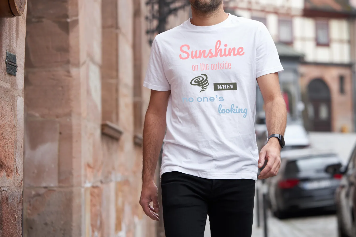 A man outside wearing a white Funny T-Shirt featuring a picture of a little hurricane and saying "Sunshine on the outside, hurricane when no one's looking".