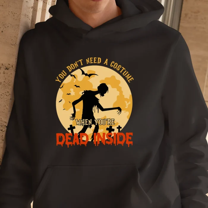 A young man outside wearing a funny Halloween Hoodie with a zombie print saying "You don't need a costume when you're dead inside". Black color