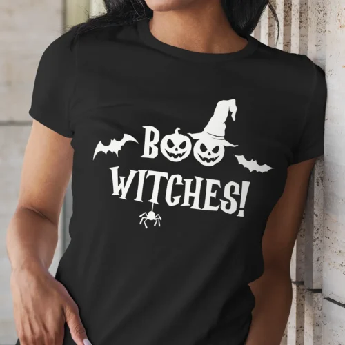 A young african-american woman outside wearing a funny Halloween T-Shirt with a witch's hat saying "Boo Witches!" Black color