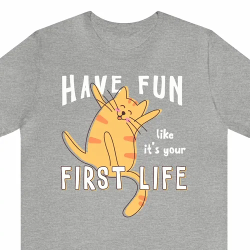 A funny t-shirt with a picture of a cute cat, saying "Have fun like it's your first life", gray